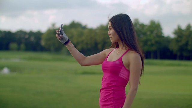 Sport woman selfie in park. Beautiful woman selfi with phone outdoor. Asian girl taking selfie photo on phone. Fitness woman posing for selfie portrait. Attractive girl selfie phone