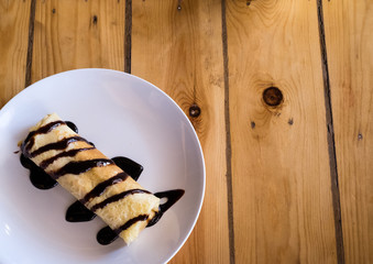 Crepes with bananas and cream on wooden table background