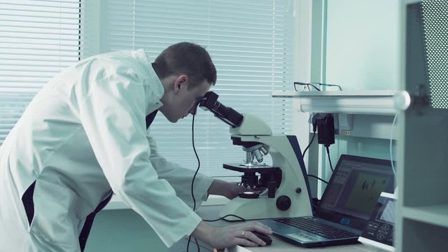 Technologist or pathologist using a microscope in a medical laboratory during a diagnostic test or while doing scientific research