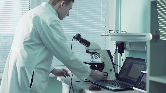 Technologist or pathologist using a microscope in a medical laboratory during a diagnostic test or while doing scientific research