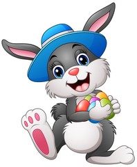 Fototapeta premium Happy easter bunny wearing a hat carrying eggs