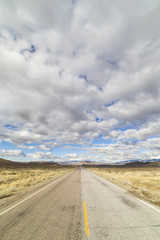 Empty rural paved road in the Nevada desert under cloudy skies.
