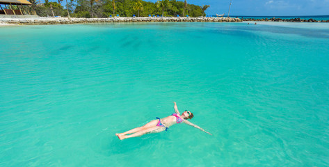 Woman floating on a back in the beautiful sea. Aruba island