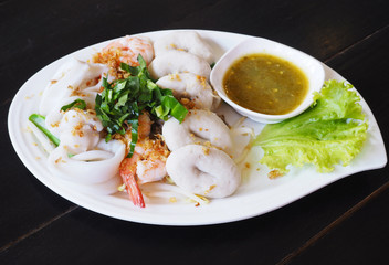 Boiled seafood dip with hot and sour sauce on white plate