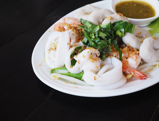 Boiled seafood dip with hot and sour sauce on white plate