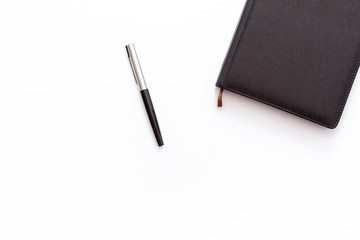 black diary and pen on a white background