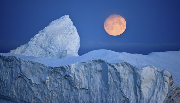 Full moon over an iceberg at dusk, Saqqaq, Disko Bay, Greenland, September 2009