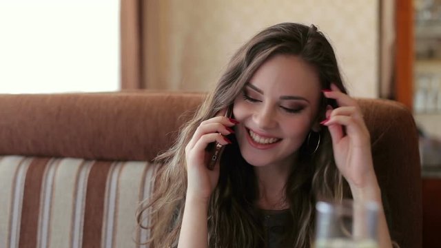 Attractive female with cute smile talking on the phone while rest in cafe.
