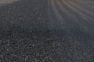 Worker operating asphalt paver machine during road construction and repairing works