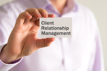 Businessman holding a card with text CRM Client Relationship Management