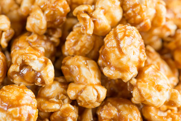 Caramel popcorn on wooden background close up