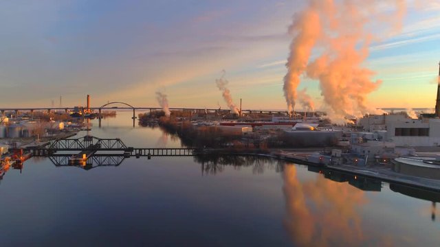 Beautiful industrial emissions reflected in still river surface, aerial view.