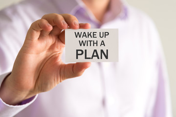 Businessman holding a card with text WAKE UP WITH A PLAN