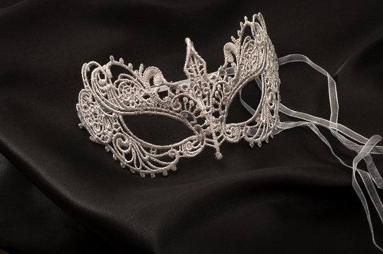 Sexuallity and eroticism concept with a beautiful grey lace masquerade vintage gothic mask on black silk