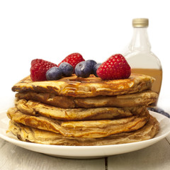 Stack of homemade pancackes with generic maple syrup bottle