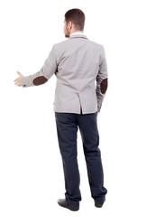 back view of businessman in jacket reaches out to shake hands