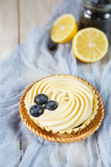Lemon tartlet with fresh blueberries white wood background