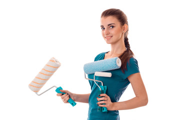 a young girl stands sideways and holding rollers for painting walls isolated on white background