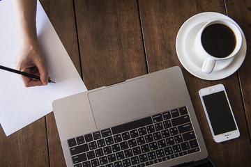 Working space , hot coffee , smartphone , laptop and hand writing