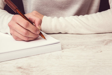 Hands writing something on the white paper. Writing a letter.
