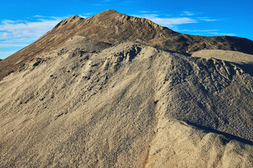 A pile of sand on a background of blue sky. Extraction of sand and gravel.