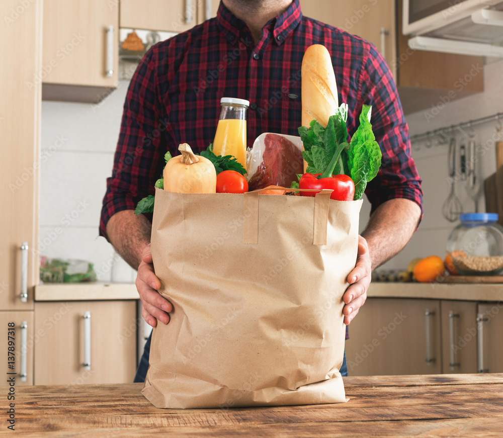 Sticker Man holding paper bag of healthy food on wooden table