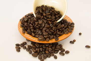 Coffee bean in a White coffee cup and a brown dish on white background.