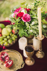 Table setting at stylish reception. Floral composition, vintage golden crockery, fruits and candles on decorated dining table.