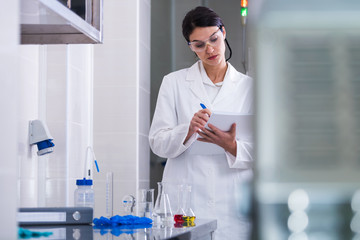 Woman scientist in laboratory writing down after lab tests