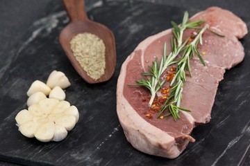 Sirloin chop, garlic and spices on black slate plate