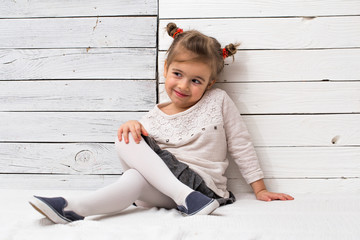Naklejka premium little cute girl school girl sitting on white wooden background