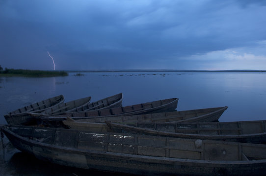 Boats moored on a lake, lightning in the distance, Lake Belau, Moldova, June 2009