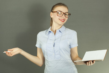 
Young smiling woman student with pen and notebook  against  gray background have emotion
