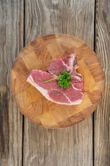 Sirloin chop and corainder leaves on wooden tray