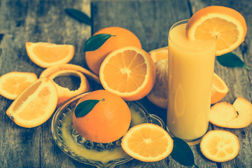 Glass of orange juice and fresh orange fruits on rustic wooden table