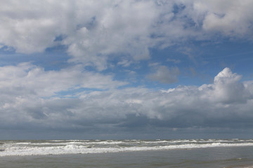 Fototapeta na wymiar Clouds and waves at the Northsea coast. Julianadorp. Beach. Coast Netherlands