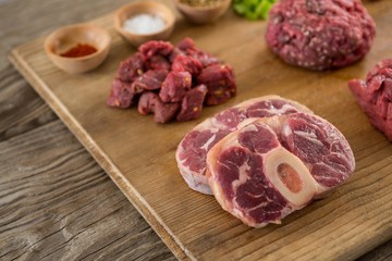 Varieties of meat and spices on wooden tray