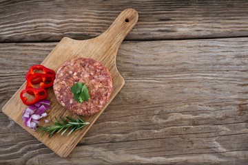 Beef patty and ingredients on wooden tray
