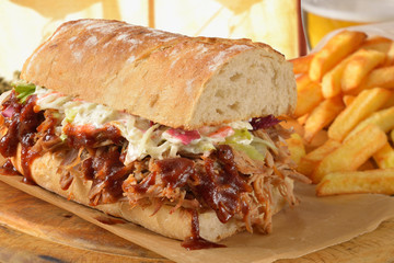 Submarine sandwich pulled pork, BBQ sauce,coleslaw fries and a glass of beer.