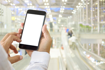 Man using smartphone in airport terminal.