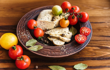 homemade cheese,tomatoes with herb spice in rural pottery.wooden background