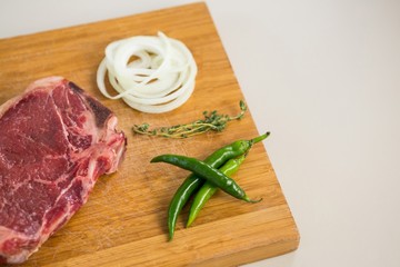 Sirloin chop, herbs and chillies on wooden tray