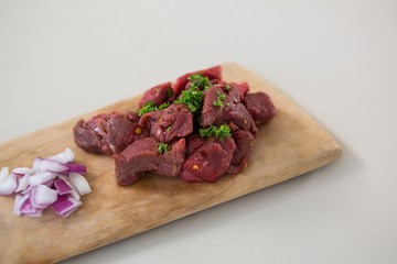 Minced beef and chopped onions on wooden tray