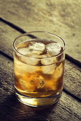 Tasty Colorful Cold Alcohol Drink Whiskey with Ice in Glass on Wooden Table. Toning.