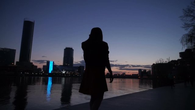 Silhouette of the girl at night on the river bank