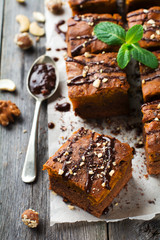 Chocolate brownie with a pumpkin on a old wooden background. Homemade Cake square pieces. Selective focus.