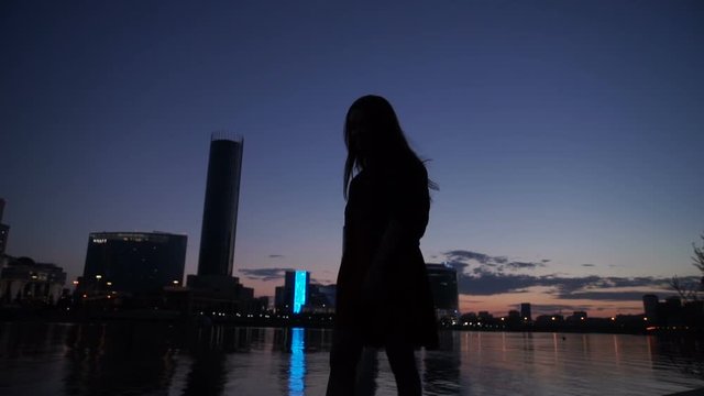 Silhouette of the girl at night on the river bank