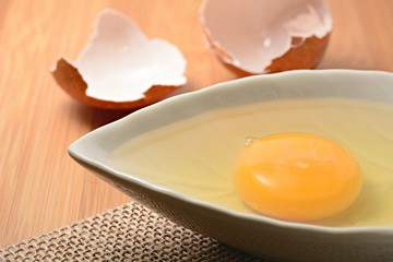 egg yolk in bowl and on wooden table