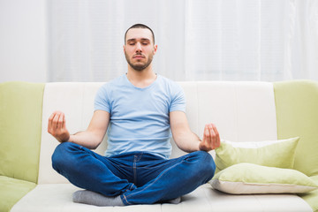 Young man enjoys meditating at his home.