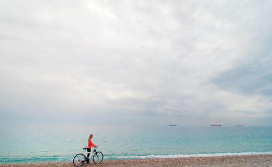 woman walking near the sea with bicycle